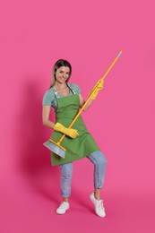 Young woman with yellow broom on pink background