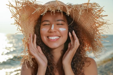 Photo of Happy African American woman with sun protection cream on face at beach