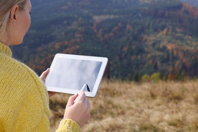 Young woman drawing with graphic tablet in mountains, closeup