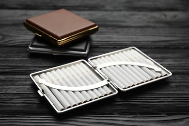 Stylish leather cigarette cases on black wooden table