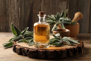 Bottle of essential sage oil and twigs on wooden table