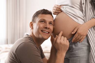 Photo of Young pregnant woman with her husband at home, closeup