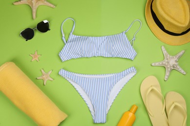 Flat lay composition with swimsuit and beach accessories on green background