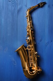 Beautiful saxophone on blue wooden background, top view