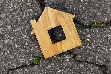 Wooden house model on cracked asphalt, top view. Earthquake disaster