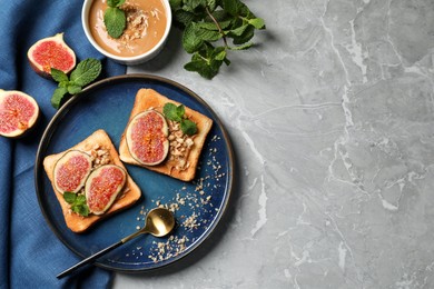 Tasty toasts served with fig, peanut butter and walnuts on light grey marble table, flat lay. Space for text