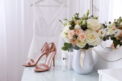 Beautiful wedding bouquet and shoes on dressing table indoors