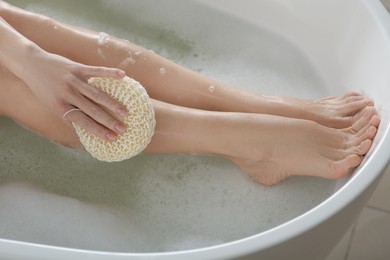 Woman rubbing her leg with sponge while taking bath, closeup