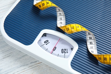 Scales and measuring tape on wooden background, closeup. Weight loss