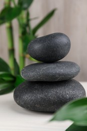 Stacked spa stones and bamboo on white wooden table, closeup