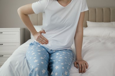Woman suffering from appendicitis inflammation on bed at home, closeup