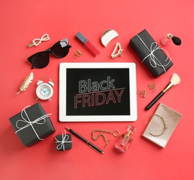 Flat lay composition with tablet, gifts and accessories on red background. Black Friday sale