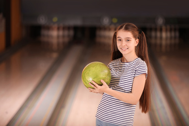 Photo of Preteen girl with ball in bowling club. Space for text