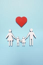 Photo of Figures of family and heart on light blue background, top view. Insurance concept
