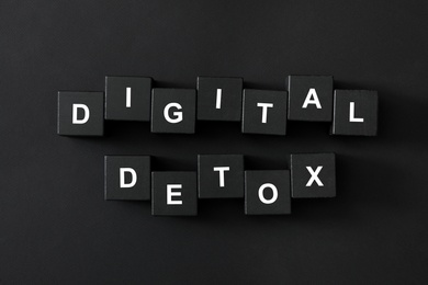 Photo of Cubes with phrase DIGITAL DETOX on black background, flat lay