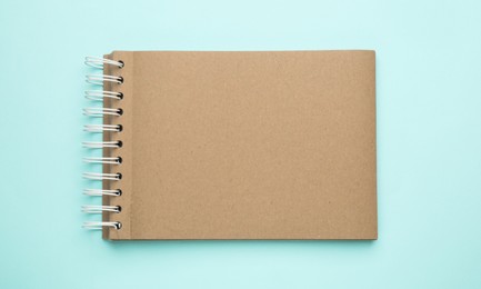 Notebook with brown paper pages on light blue background, top view