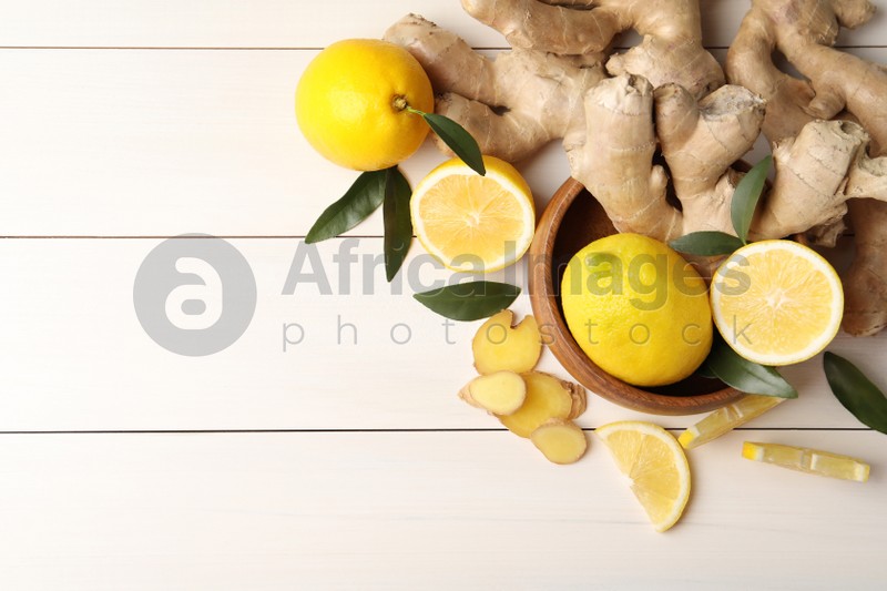 Photo of Fresh lemons and ginger on white wooden table, flat lay. Space for text