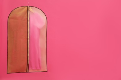 Garment bag with dress on pink background. Space for text