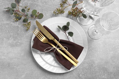 Photo of Stylish table setting with cutlery and eucalyptus leaves, flat lay