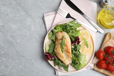 Photo of Delicious cooked chicken and fresh salad served on grey marble table, flat lay with space for text. Healthy meals from air fryer