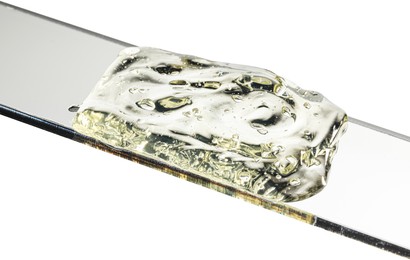 Photo of Glass slide with clear face gel on white background, closeup