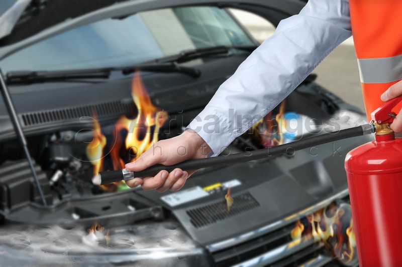 Man with fire extinguisher near car in flame outdoors, closeup
