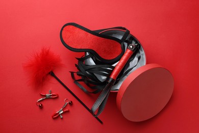 Gift box with different sex toys on red background, flat lay
