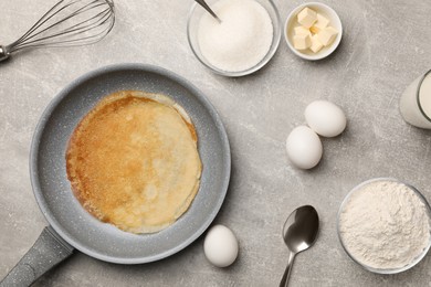 Frying pan with delicious crepe and ingredients on grey table, flat lay