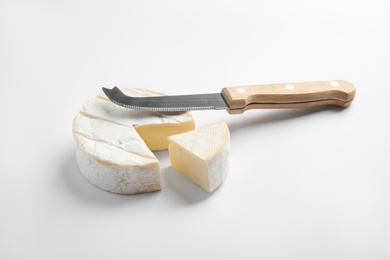 Cut Camembert cheese and knife on white background