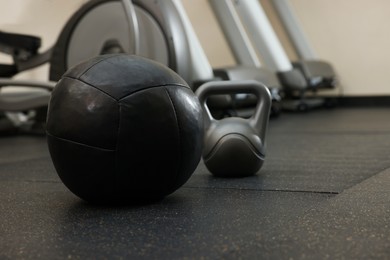 Black medicine ball and kettlebell on floor in gym