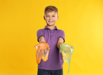 Preteen boy with slime on yellow background