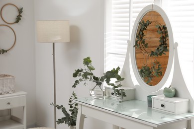 Photo of Stylish dressing table decorated with beautiful eucalyptus branches indoors