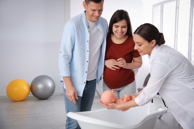 Man with pregnant wife learning how to bathe baby at courses for expectant parents indoors