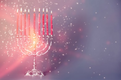 Silver menorah with burning candles on color background, space for text. Hanukkah celebration