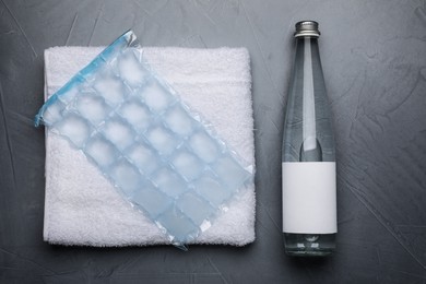 Bottle of water, ice pack and towel on grey background, flat lay. Heat stroke treatment