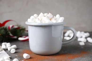Cup of tasty hot drink with marshmallows on grey table