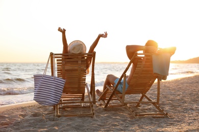 Young couple relaxing in deck chairs on beach near sea