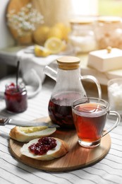 Aromatic tea and slice of bread with jam on table
