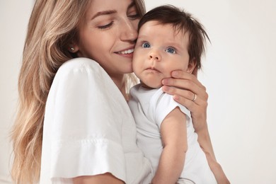 Photo of Mother hugging her cute little baby on white background, closeup
