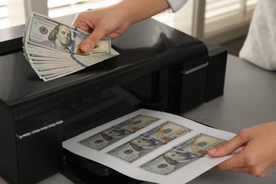 Counterfeiter printing dollar banknotes at grey table indoors, closeup. Fake money concept