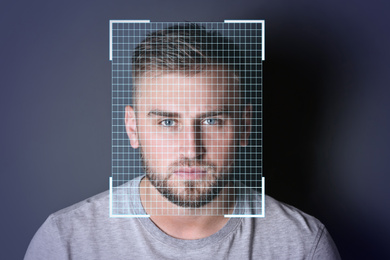 Facial recognition system. Young man with scanner frame and digital grid on dark background