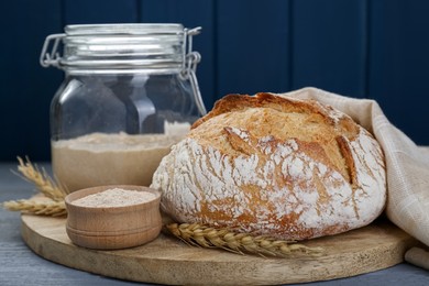 Photo of Freshly baked bread, flour and sourdough on grey wooden table