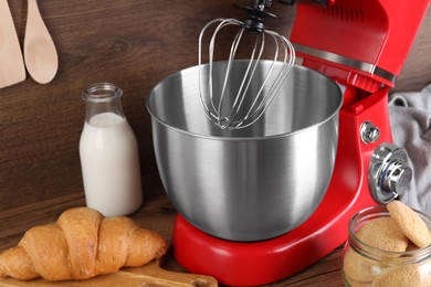 Photo of Modern red stand mixer, croissant and cookies on wooden table, closeup