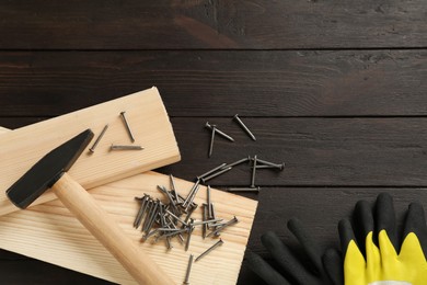 Photo of Hammer, planks, gloves and metal nails on wooden table, flat lay. Space for text