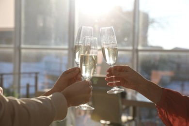 Photo of People clinking glasses of champagne in office, closeup. Holiday cheer and drink