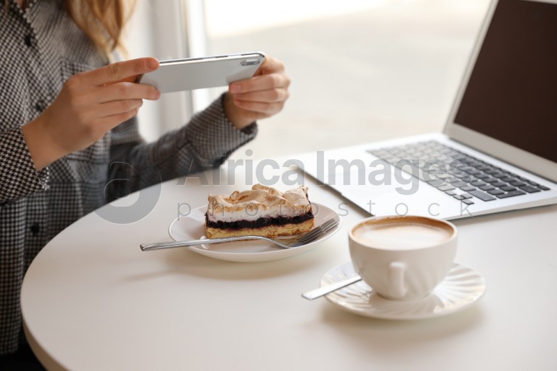 Young blogger taking photo of dessert in cafe, closeup