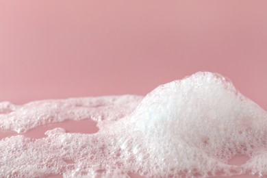 Fluffy bath foam on pink background, closeup. Care product