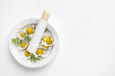Hygienic lipstick, chamomile flowers and marble tray on white background, top view