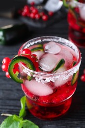 Photo of Spicy red currant cocktail with jalapeno on black wooden table, closeup