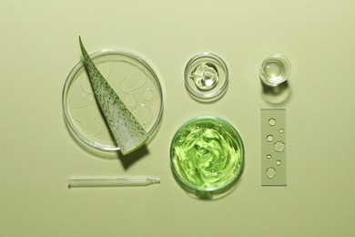 Organic cosmetic product, natural ingredients and laboratory glassware on green background, flat lay